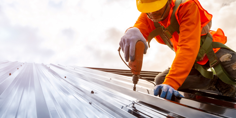 A construction worker installing a new metal roofing sheet type, known for its durability and weather resistance.